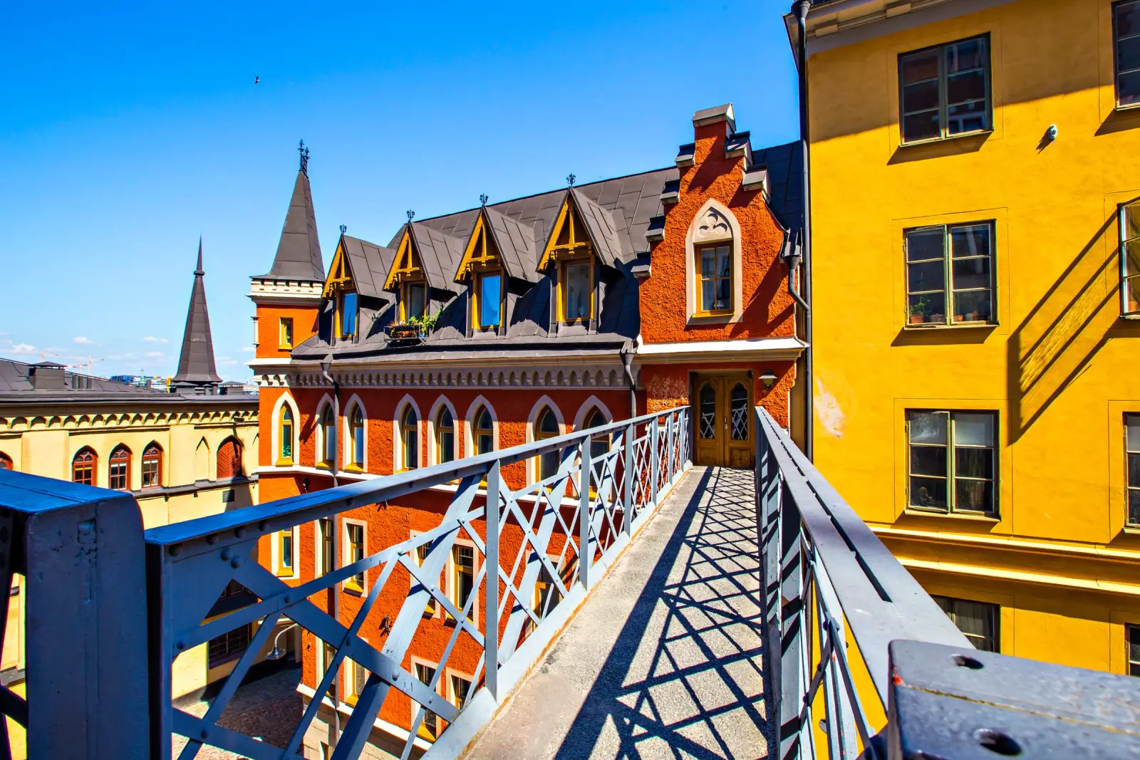 Sunlit footbridge between colorful historic buildings at Mariaberget in Södermalm