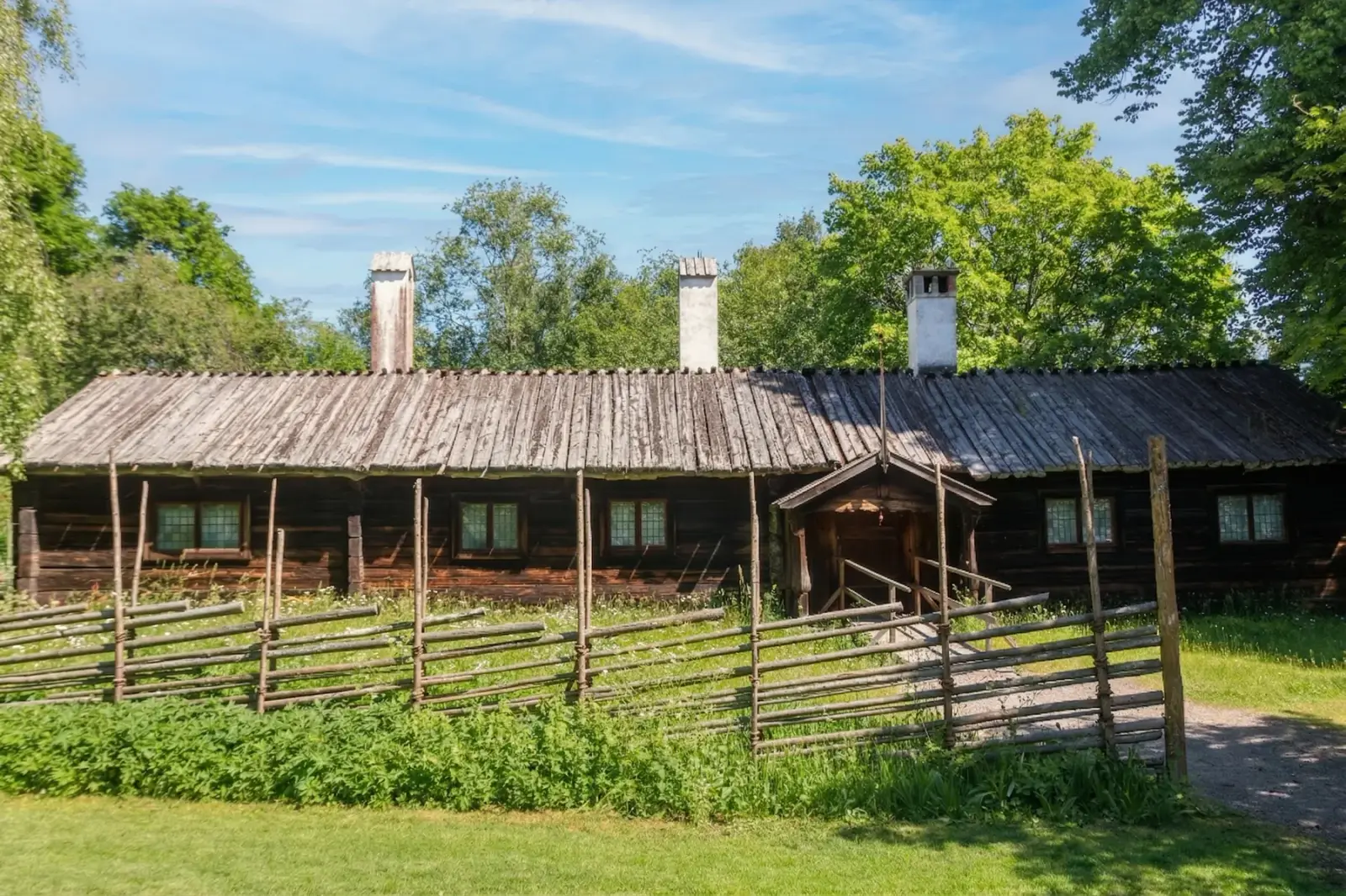 Ferme traditionnelle en bois à Skansen derrière une clôture rustique par une journée ensoleillée