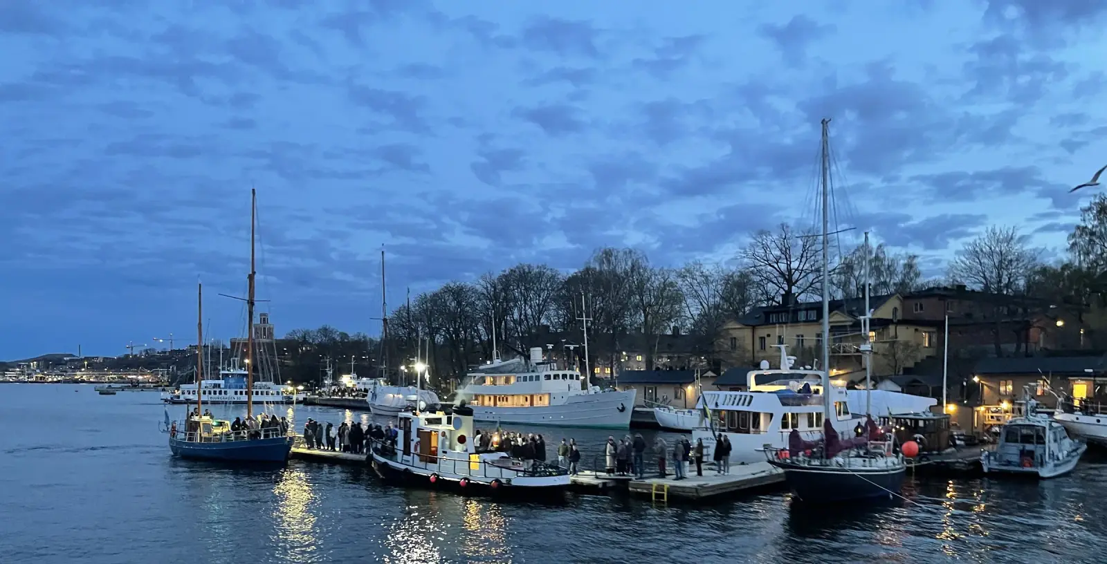 Vue à l'heure bleue des bateaux amarrés le long d'un quai éclairé près de Skeppsholmen à Stockholm