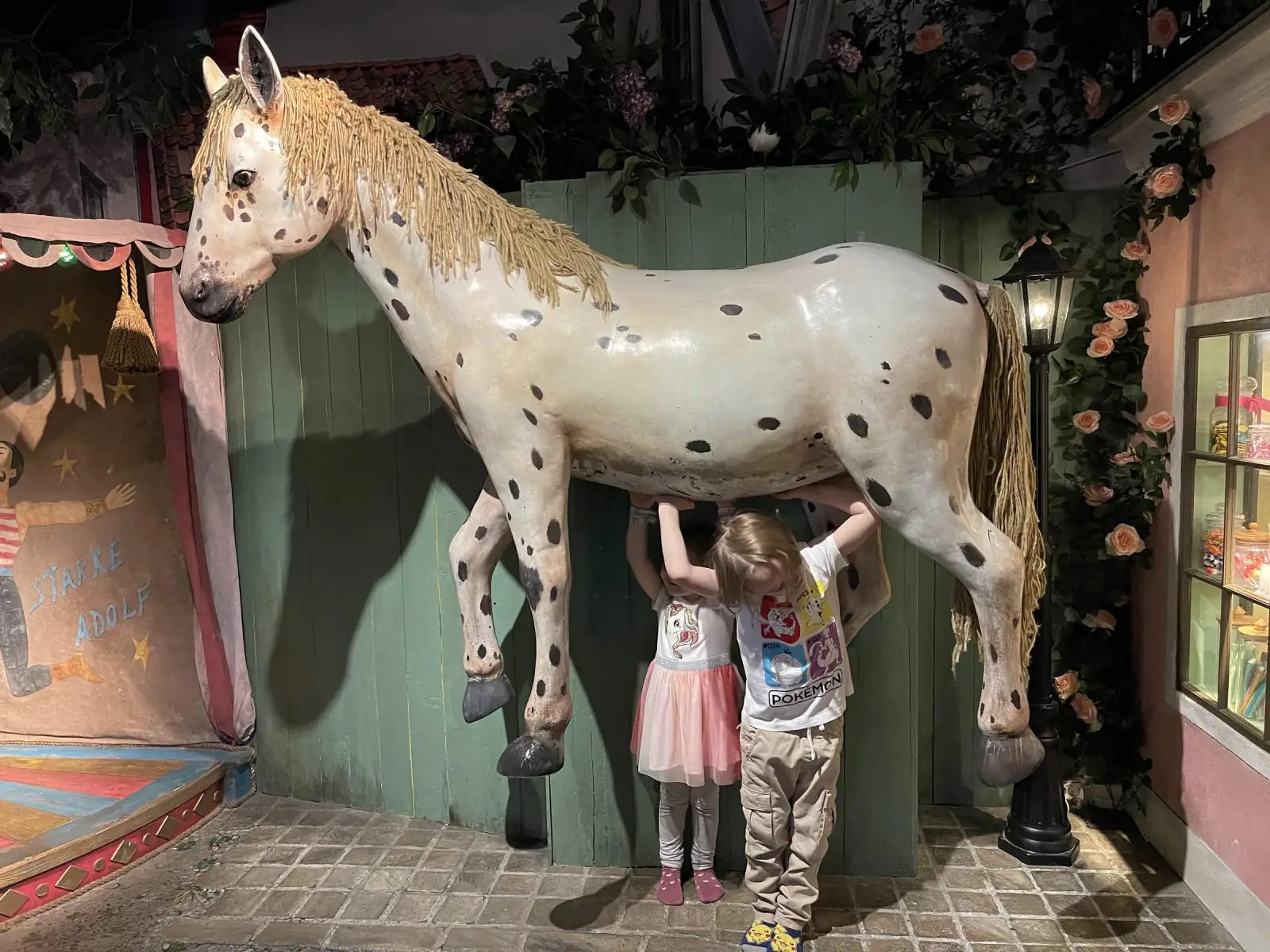 Deux enfants debout sous le cheval tacheté de Junibacken dans Stockholm
