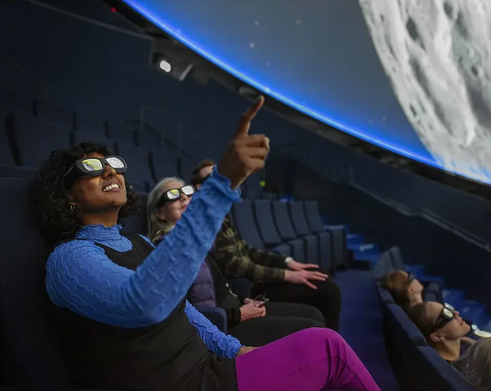 Visiteurs portant des lunettes 3D à l’intérieur du Wisdome Stockholm sous une grande projection en forme de dôme