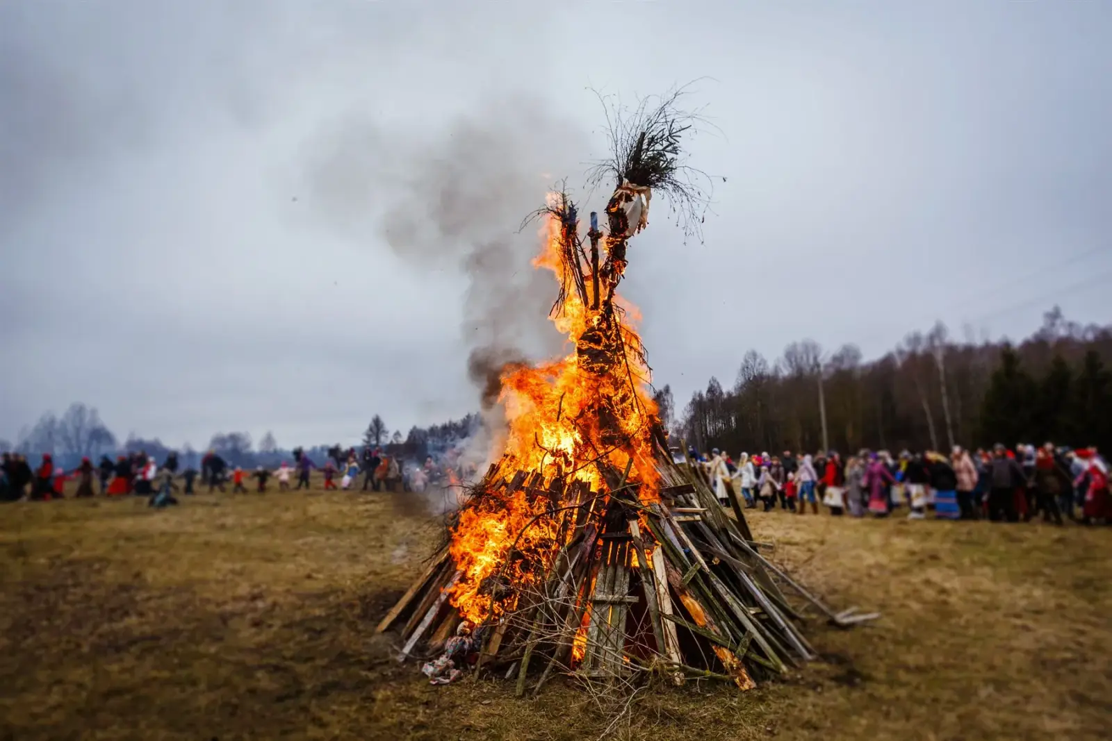Feu de joie traditionnel Valborg brûlant dans un champ ouvert avec des personnes rassemblées autour